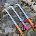 Three long metal scrapers with curved silver blades and colored handles, placed on a rocky outdoor ground. The handles are orange, pink, and red, each printed with the brand name 'SCRAPERS'.