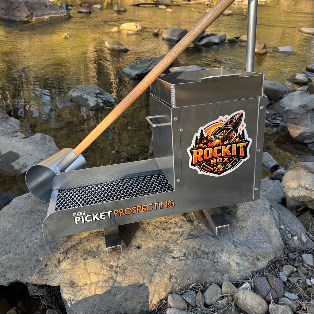 Aluminium rocker box placed on a large rock in a creek setting. Displaying expanded mesh and a classifying sieve.