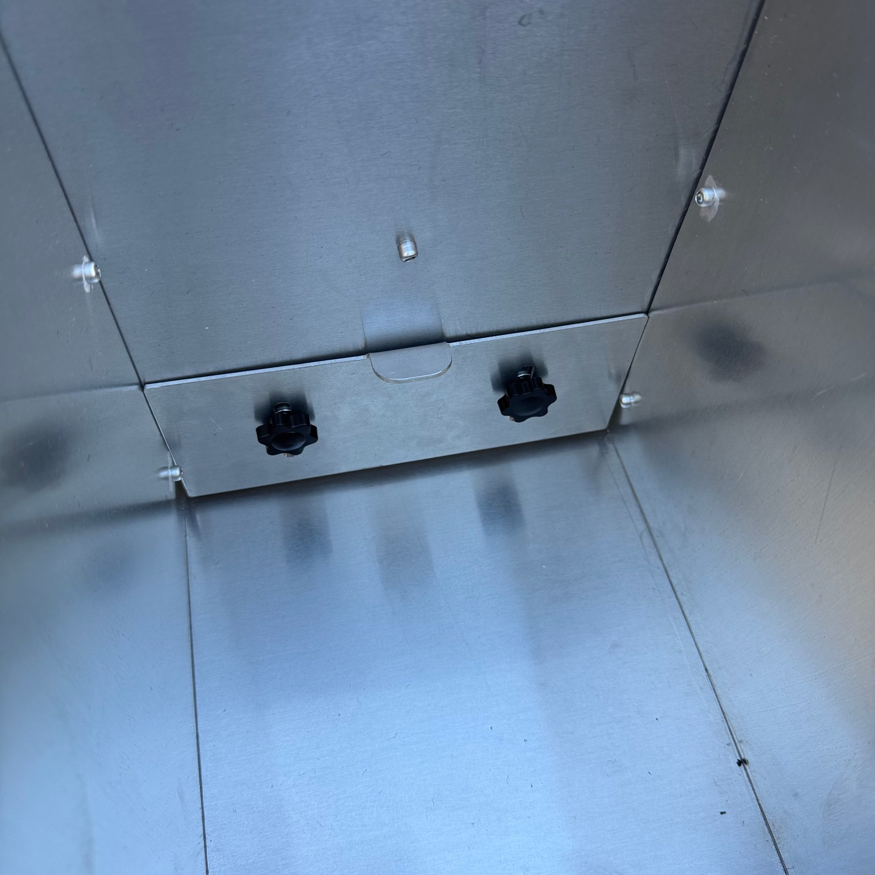 Close-up of the bottom interior corner of the aluminium Franken sluice showing two black knobs on an aluminium water gate.